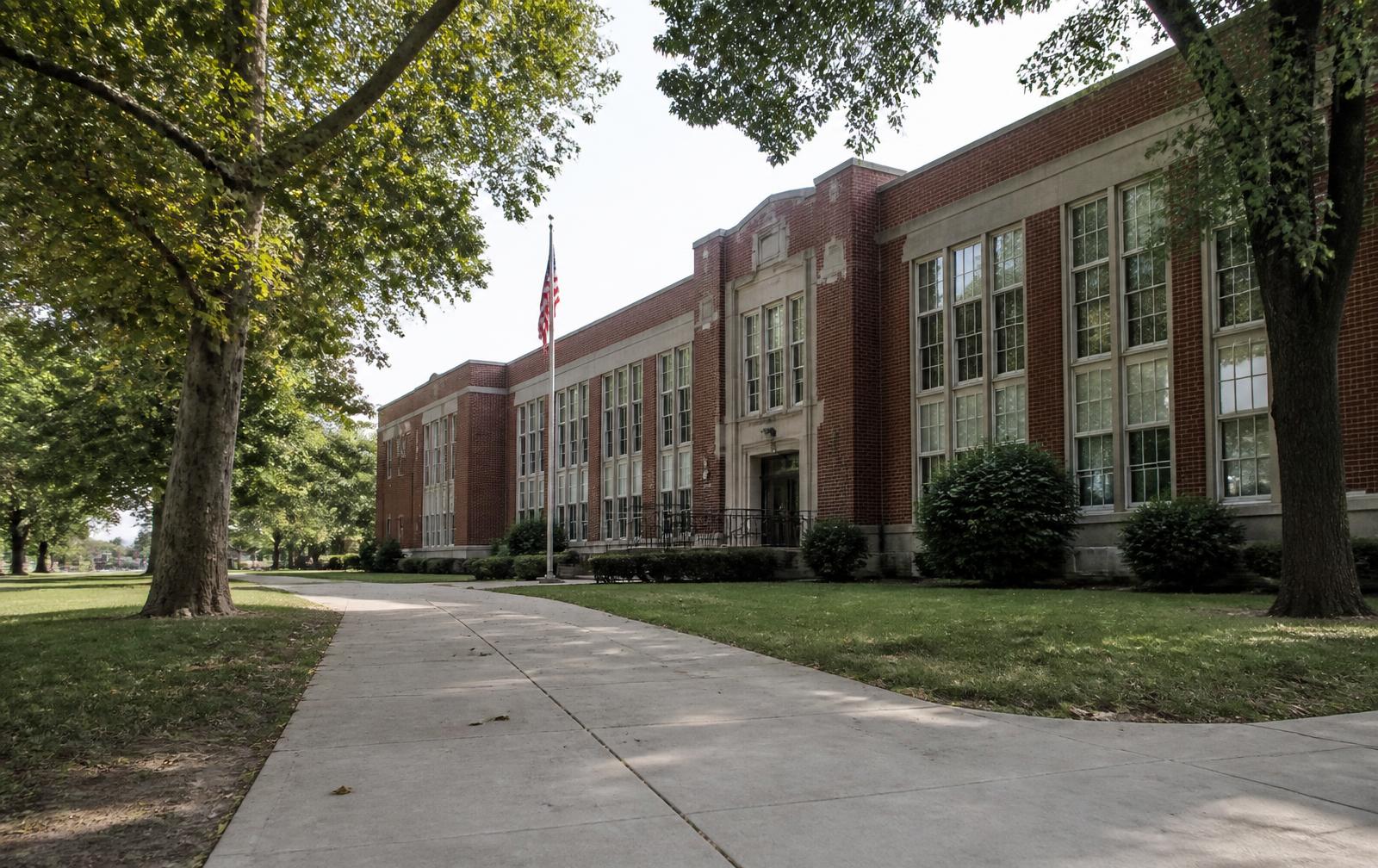 Mid-century brick school building shaded by mature trees